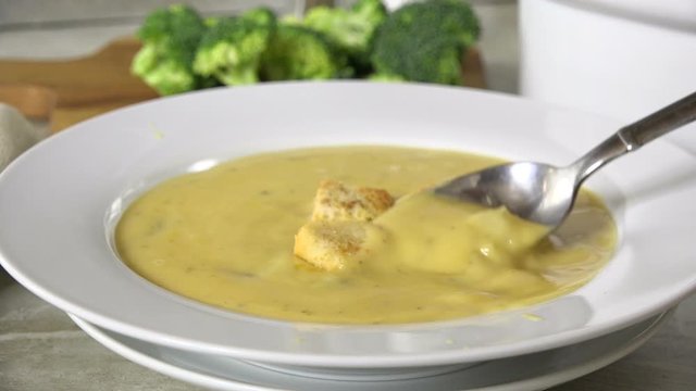 Adding croutons to broccoli cheese soup and eating a spoonful