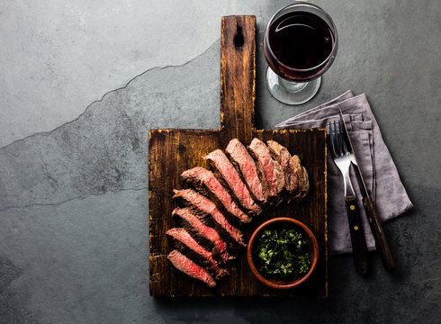 Slices Of Beef Medium Rare Steak On Wooden Board, Glass Of Red Wine