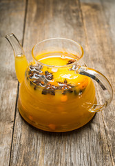 Sea buckthorn hot drink with orange juice and spices in glass teapot. Selective focus. Shallow depth of field.