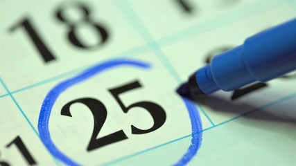 25th – twenty-fifth day of the month. The woman marks the calendar date with a blue marker....