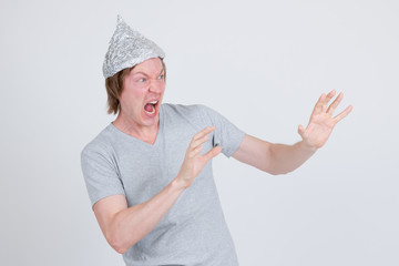 Stressed young man with tinfoil hat as conspiracy theory concept looking scared