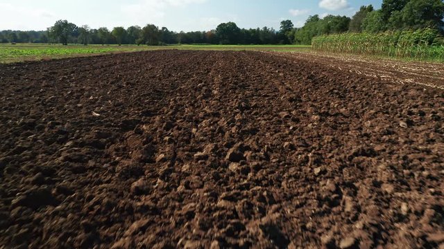 Ploughed field in autumn, flyover, hedges and trees in background, agiculture and cultivating soil concept