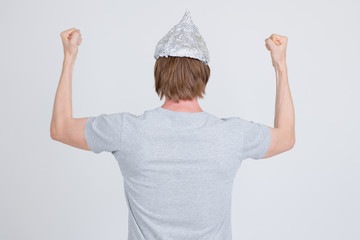 Rear view of young man with tinfoil hat as conspiracy theory concept raising fists