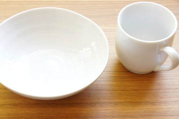 Fototapeta na wymiar 木のテーブルに置かれた白い皿とマグカップ