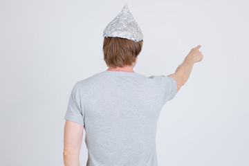 Rear view of young man with tinfoil hat as conspiracy theory concept directing
