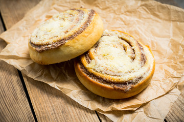 Fresh cinnamon buns on the rustic wooden background. Selective focus. Shallow depth of field.