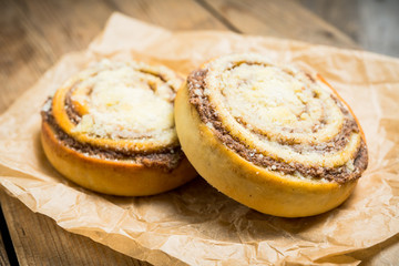 Fresh cinnamon buns on the rustic wooden background. Selective focus. Shallow depth of field.