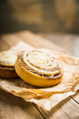 Fresh cinnamon buns on the rustic wooden background. Selective focus. Shallow depth of field.