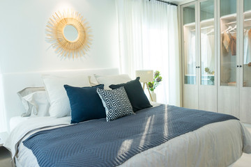 Modern bedroom in minimalist white and blue interior tone with with comfy pillow, side table and...