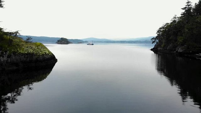 Aerial footage of a small cove and a bay with a fishing trawler moored at the end near Sooke, BC. - 4K 24FPS