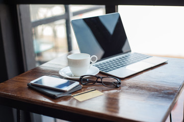 Working desk with laptop and coffee cup early in the morning.