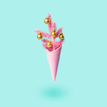 Soaring Painted pink ice cream cone with christmas tree and golden balls. Minimal holiday concept. Modern greeting card
