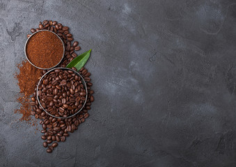 Fresh raw organic coffee beans with ground powder and coffee trea leaf on black background.
