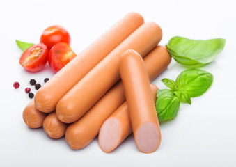 Classic boiled meat pork sausages with pepper and basil and cherry tomatoes on white background.