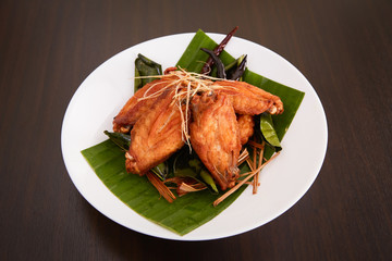 Herbal fried chicken wings on a white plate on a wooden floor