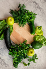 Fresh organic vegetables-zucchini, cucumbers, peppers, avocado, greens, green apples on a light background, top view.Healthy lifestyle, green diet. The view from the top, place for text.