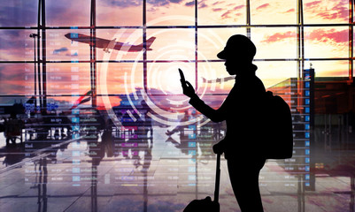 Airport terminal at sunset with passengers looking smartphone. - 298205955