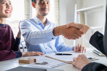 Asian young family couple handshake with property real estate agent after made agreement home loan contract purchase of their