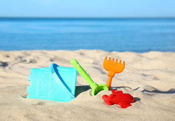 Fototapeta na wymiar Set of plastic beach toys on sand near sea