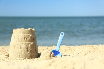 Beautiful view of beach with sand figure and shovel near sea. Space for text © New Africa