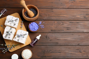 Flat lay composition with hand made soap bars and lavender flowers on wooden table, space for text