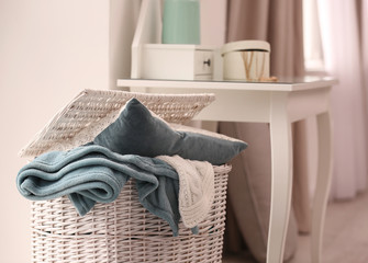 Basket with blankets and pillow near dresser indoors