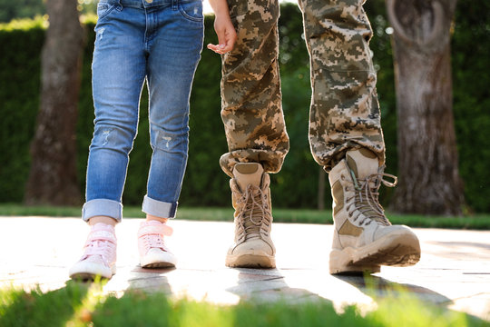 Father in military uniform walking with his daughter at sunny park, closeup