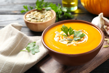 Delicious pumpkin soup in bowl on wooden table - Powered by Adobe