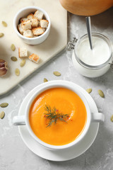 Delicious pumpkin soup in bowl on marble table, flat lay