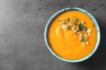 Delicious pumpkin soup in bowl on grey table, top view. Space for text