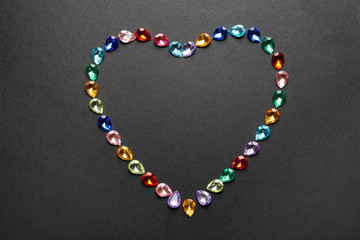 Heart made of different beautiful gemstones on black background, flat lay. Space for text