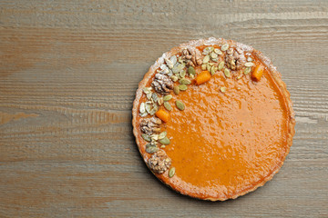 Delicious fresh homemade pumpkin pie on wooden table, top view. Space for text