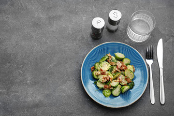 Delicious cooked Brussels sprouts with bacon served on grey table, flat lay. Space for text