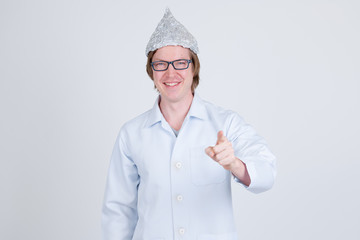 Happy young man doctor with tinfoil hat pointing at camera