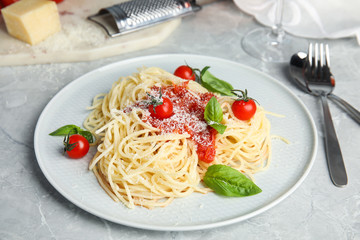 Tasty pasta with tomatoes, cheese and basil on light grey marble table