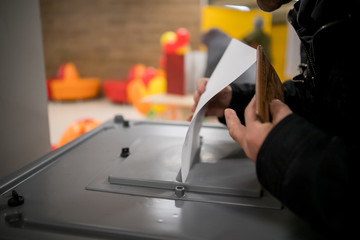 Obraz premium Hand of a person casting a vote into the ballot box during elections