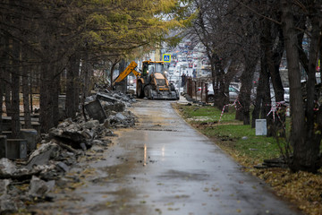 excavator works in the city, dismantling the fence in the city park