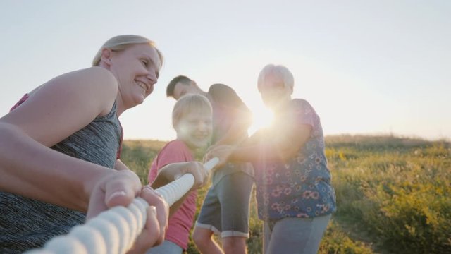 Cheerful family competes in tug of war at summer camp