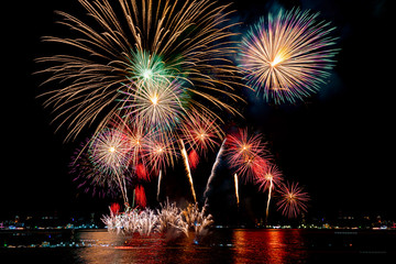 Amazing beautiful colorful fireworks display on celebration night, showing on the sea beach with multi color of reflection on water