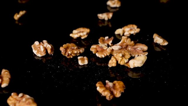 Wallnuts falling on the black reflective surface. Healthy food, source of good proteins and fats, omega 3 and keto diet plan