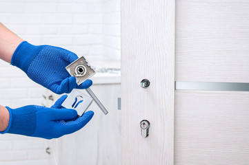 The guy installs new handles and a lock for the door to the room. Repair in the house. The guy in...