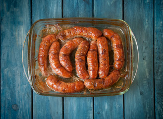 kupaty baked in the oven in a glass container on a blue background