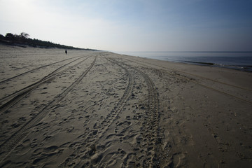 Empty beach with a lone woman walking off in the distance