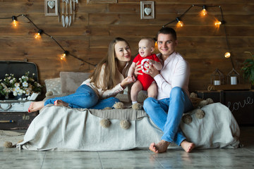 Fototapeta na wymiar Parents and their child sitting on bed. Mom, dad and baby. Portrait of young family. Happy family life. Man was born.