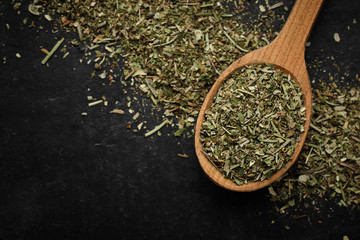 herbs of Provence seasoning for food in wooden spoon and black background isolated. macro shot © Евгений Логвиненко