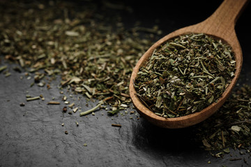 herbs of Provence seasoning for food in wooden spoon and black background isolated. macro shot