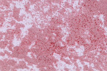 A pale pink sand with crimson particles scattered on white background