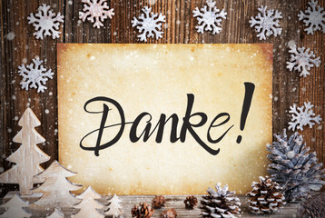 Obraz na płótnie Canvas Old Paper With German Text Danke Means Thank You. Christmas Decoration Like Tree, Fir Cone And Snow. Brown Wooden Background