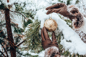 Girl holds a Christmas toy. Hands in leather gloves closeup. Seasonal holidays and celebrations. Traditional New Year and Christmas decor.