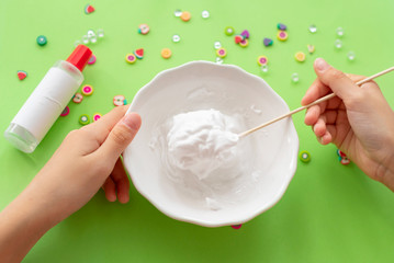 a girl making slime herself. child making slime on green background. 